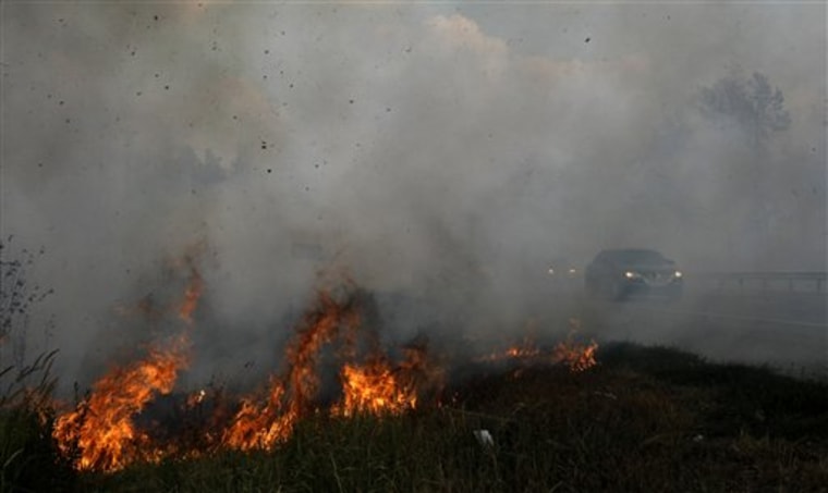 Cars ride along the Moscow-Nizhny Novgorod highway, just few meters from a grassfire caused by a wildfire near the village of Plotava, east of Moscow, Saturday. The fires have destroyed provincial towns and villages, and together with the drought have cost Russia a third of its wheat crop. 